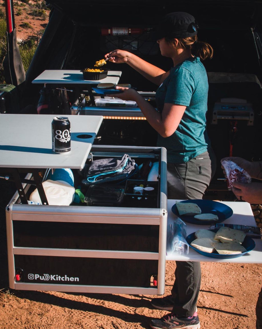Slide out camping kitchen mounted in truck bed, woman preparing lunch at campground in Moab Desert